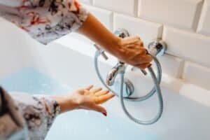 Hands adjusting the water temperature on a tap: low flow is the primary reason why a Junkers water heater won't turn on